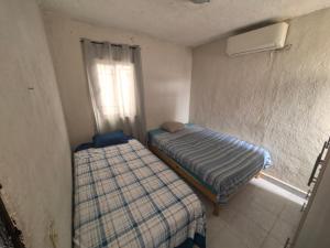 two beds in a small room with a window at Casa Constructor staff colaboradores in Cabo San Lucas