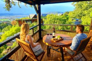 a man and woman sitting at a table on a deck at Paradise Private Zen Studios in Knysna