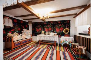 a room with a table and a floral wall at Pensiunea Casa Sobarului in Molovata