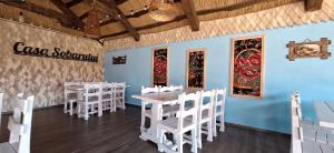 a dining room with white tables and white chairs at Pensiunea Casa Sobarului in Molovata