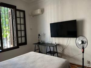 a bedroom with a bed and a flat screen tv on the wall at Casa en Pocitos in Montevideo