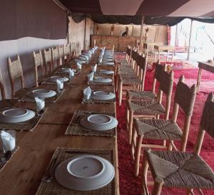a long table in a tent with chairs and plates at ITRANE Agafay in Marrakesh