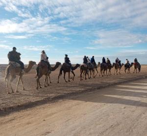 a group of people riding horses on a dirt road at ITRANE Agafay in Marrakesh