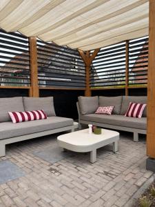 a patio with two couches and a coffee table at Chalet 't Zwaluwnest in Aagtekerke