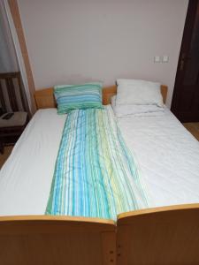 a bed with a striped sheet on top of it at Vila Spas in Mataruška Banja