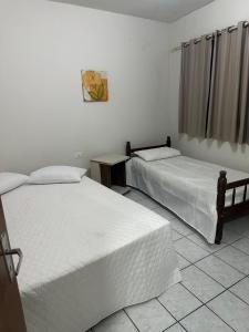 two beds in a room with white walls at Apartamento próximo da Praça Mestre Dominguinhos in Garanhuns