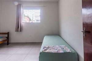 a room with a green bed in a room with a window at Apto para 8 pessoas com Garagem e Churrasqueira in Pará de Minas