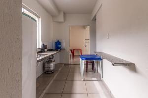 a kitchen with a table and a blue stool at Apto para 8 pessoas com Garagem e Churrasqueira in Pará de Minas