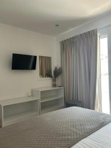 a bedroom with a bed and a tv and a window at Fiosal Apartments 3 in Skiathos