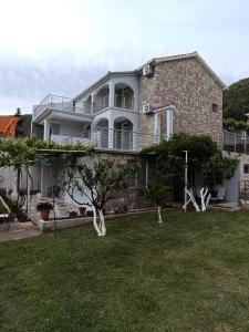 a large white house with a lawn in front of it at Studio apartmani AHUS in Petrovac na Moru