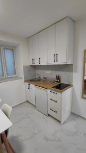 a kitchen with white cabinets and a counter top at Studio apartmani AHUS in Petrovac na Moru