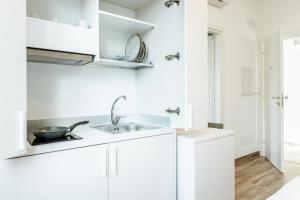a kitchen with white cabinets and a sink at Silvia's Luxury Suites by RentMax in Canegrate +63 photos