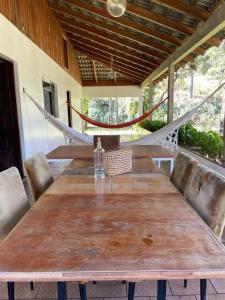 a long wooden table with chairs and a hammock at Memora Guesthouse Bateias - Casa Inteira ou quartos em chácara in Campo Largo +82 photos