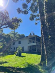 a white house with trees in front of it at Memora Guesthouse Bateias - Casa Inteira ou quartos em chácara in Campo Largo