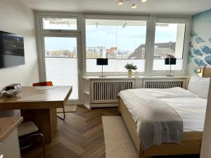 a bedroom with a bed and a desk and two windows at Boje in Westerland