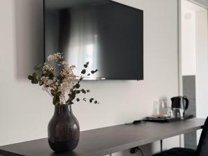 a black vase with flowers sitting on a table at MiDaMi 24h Hotel Self-Checkin in Schwanau