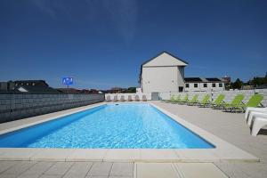 a large swimming pool with chairs and a church at Comfortable holiday homes with a summer pool in Jarosławiec