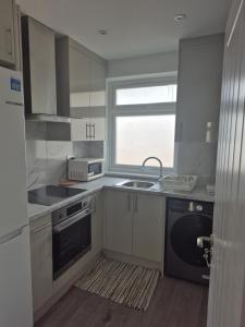 a kitchen with white cabinets and a sink and a window at One bed flat in UB5 in Northolt