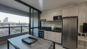 a kitchen with a stainless steel refrigerator and a table at Studio Amplo e Aconchegante com 2 Camas in Campo Grande