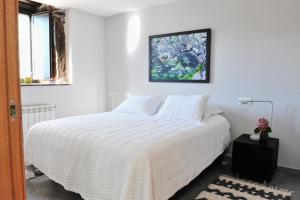a white bedroom with a bed and a picture on the wall at Casa Yañez in Chantada