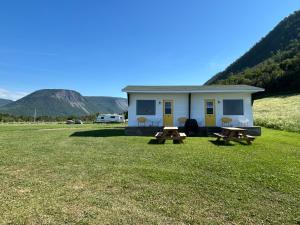 a tiny house with two picnic tables in a field at Chalets Camping Bernatchez in Mont-saint-pierre