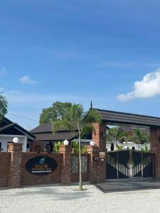 a brick building with a gate and a palm tree at RAZAK GUEST HOUSE in Setiu