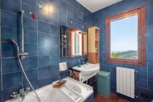 a blue tiled bathroom with a tub and a sink at Domu de Zita in Poggio