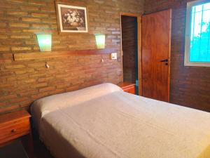 a bedroom with a bed and a brick wall at Cabañas Llajta Sumaj in Las Calles