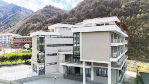 Ein weißes Gebäude vor einem Berg im Hintergrund in der Unterkunft Hotel ERALD in Peshkopi
