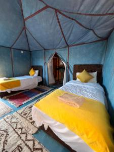 a bedroom with two beds in a tent at Elite Sahara Desert Camp in Merzouga