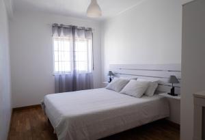 a white bedroom with a bed and a window at Baleal Holiday House in Baleal