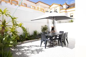a table and chairs with an umbrella on a patio at Baleal Holiday House in Baleal