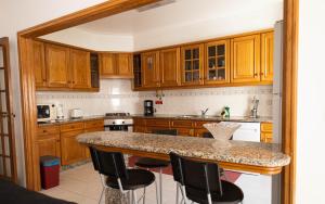 a kitchen with wooden cabinets and a counter with bar stools at Baleal Holiday House in Baleal