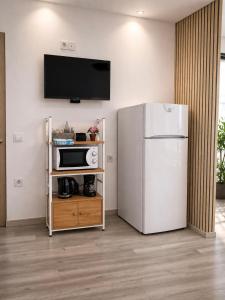 a kitchen with a refrigerator and a tv on a wall at Eleni`s apartment Gialova, Giorgos House in Gialova