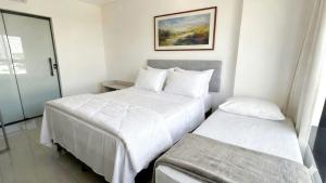 two beds in a hotel room with white sheets at Studio Amplo e Aconchegante com 2 Camas in Campo Grande +8 photos