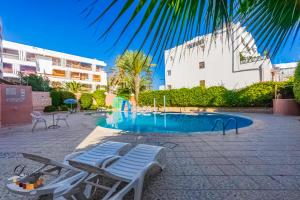 a swimming pool with two lounge chairs and a building at Hôtel Résidence Louban in Agadir