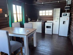 a kitchen with white appliances and a table and chairs at La Escondida in Estación Monte