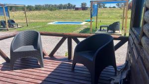 two chairs sitting on a porch with a picnic table and a playground at La Escondida in Estación Monte