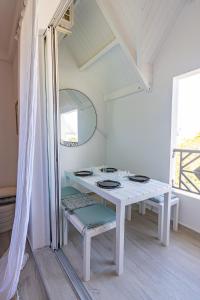 Ein weißer Tisch und Stühle in einem Raum mit einem Spiegel in der Unterkunft Mare Gaillard in Le Gosier