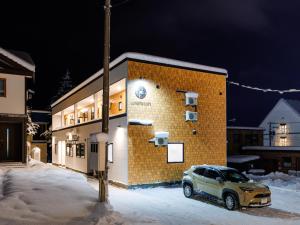 a car parked in front of a building in the snow at tonaResort Furano in Furano