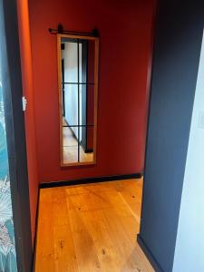 a red room with a mirror and a wooden floor at Suite La Clé de la Liberté Maison Like and Love 25m2 avec coin salon in Duclair