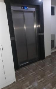 a metal elevator door in a room with a tile floor at Colman Apart Central in Ciudad del Este