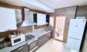a kitchen with a stove and a sink and a microwave at Agréable appartement familial avec Piscine - City Center in Fez