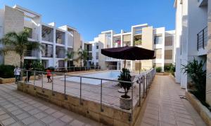 a person standing next to a pool with an umbrella at Agréable appartement familial avec Piscine - City Center in Fez