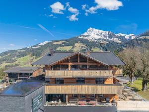 a large wooden building with mountains in the background at Das Kitz - Chalet Steuerberg Kitzbühel in Kitzbühel