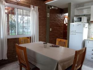 a kitchen with a table with chairs and a white refrigerator at Cabañas Llajta Sumaj in Las Calles