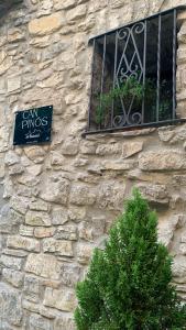 a sign on a stone building with a tree in front of a window at CAN PINÓS de GUIMERÀ in Guimerá