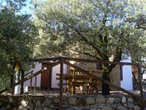 a house with a tree and a stone wall at Casas Rurales Cortijos el Encinar in Torres