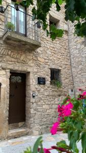 a stone building with a brown door and pink flowers at CAN PINÓS de GUIMERÀ in Guimerá +39 photos
