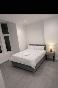 a white bedroom with a bed and a night stand at The Coach House in Bradford